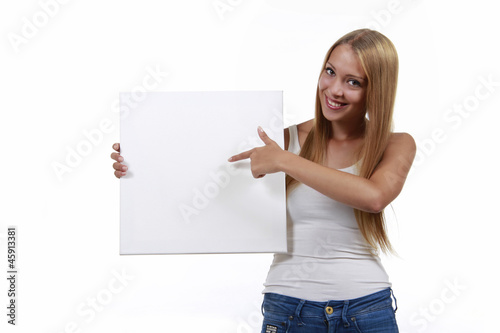 Junge hübsche Frau zeigt auf leeres Plakat