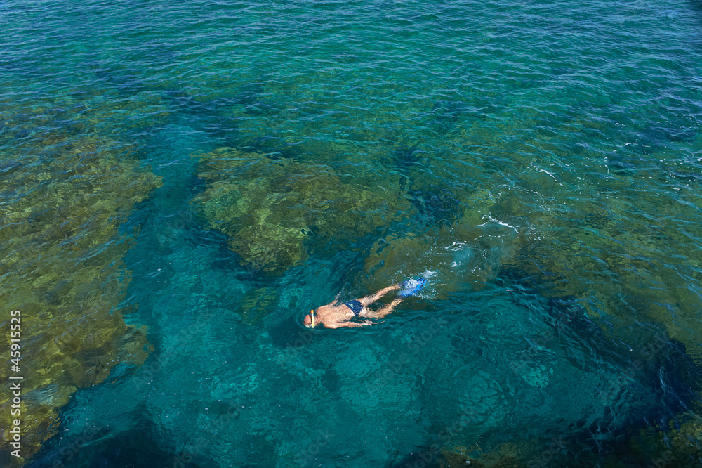 Young man snorkeling in transparent shallow ocean. Canary Islands, Lanzarote, Charco del Palo, Spain.