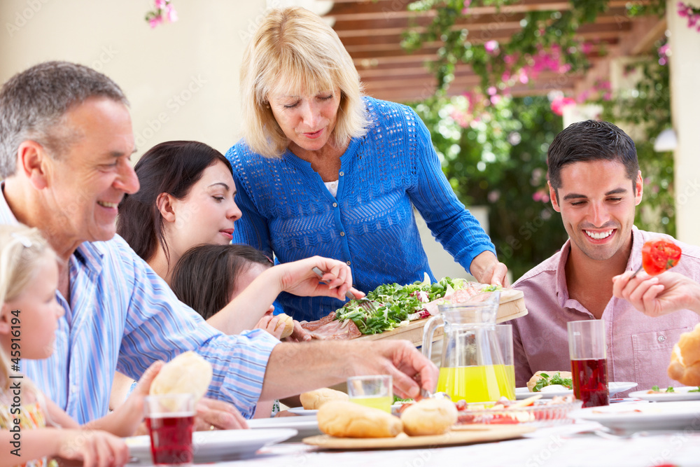 Senior Woman Serving At Multi Generation Family Meal