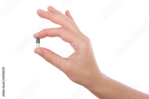 Hand holding a capsule or pill isolated on white photo