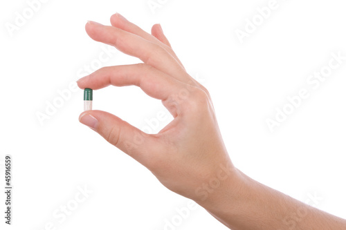 Hand holding a capsule or pill isolated on white