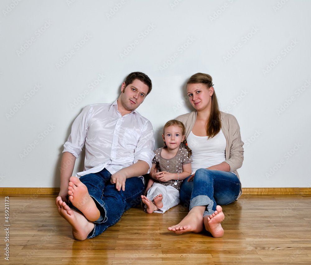 Happy family sitting on the floor against the wall Happy family sitting on the floor against the wall