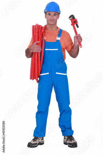 Tradesman holding corrugated tubing and a pipe wrench
