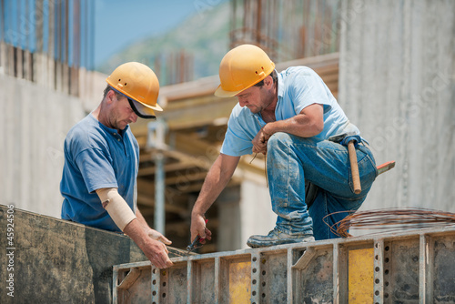 Two construction workers installing concrete formwork frames photo
