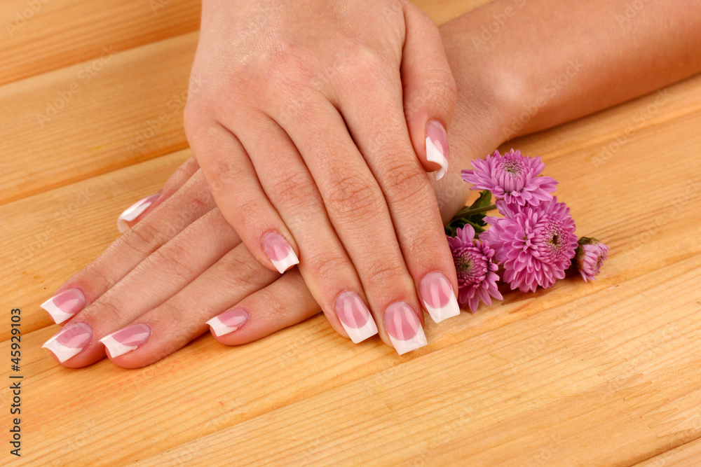 Fototapeta premium Woman hands with french manicure and flowers