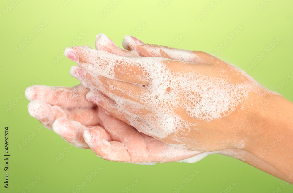 Woman's hands in soapsuds, on green background close-up Woman's hands in soapsuds, on green background close-up