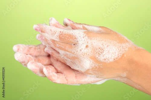 Woman s hands in soapsuds  on green background close-up