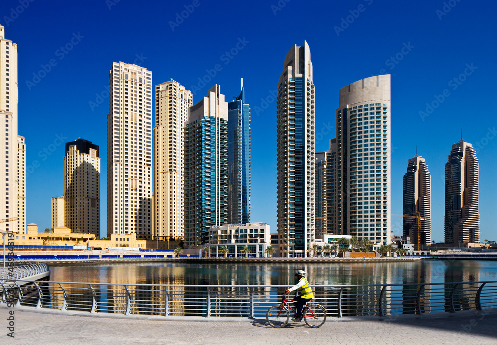 Fototapeta premium A cyclist cycles the Marina walk, Dubai Marina and JBR