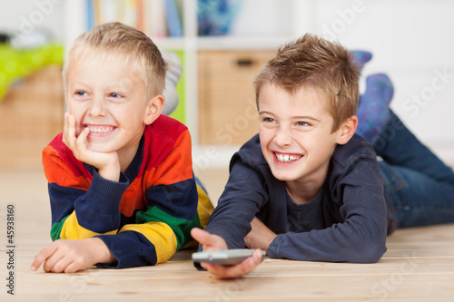 zwei lachende kinder mit fernbedienung