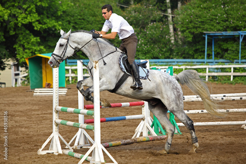 Jockey jump on horse over barrier on hippodrome © Pavel Losevsky