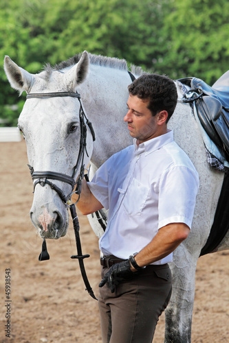 Jockey in gloves hug horse on hippodrome