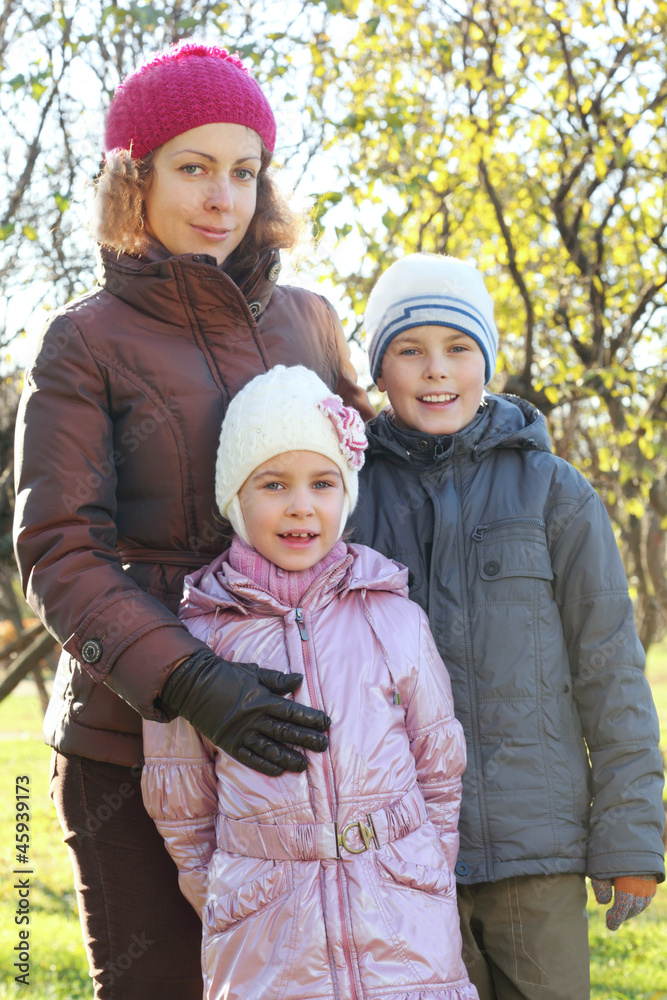 Mother hug son, daughter in autumn forest, focus on girl Mother hug son, daughter in autumn forest, focus on girl