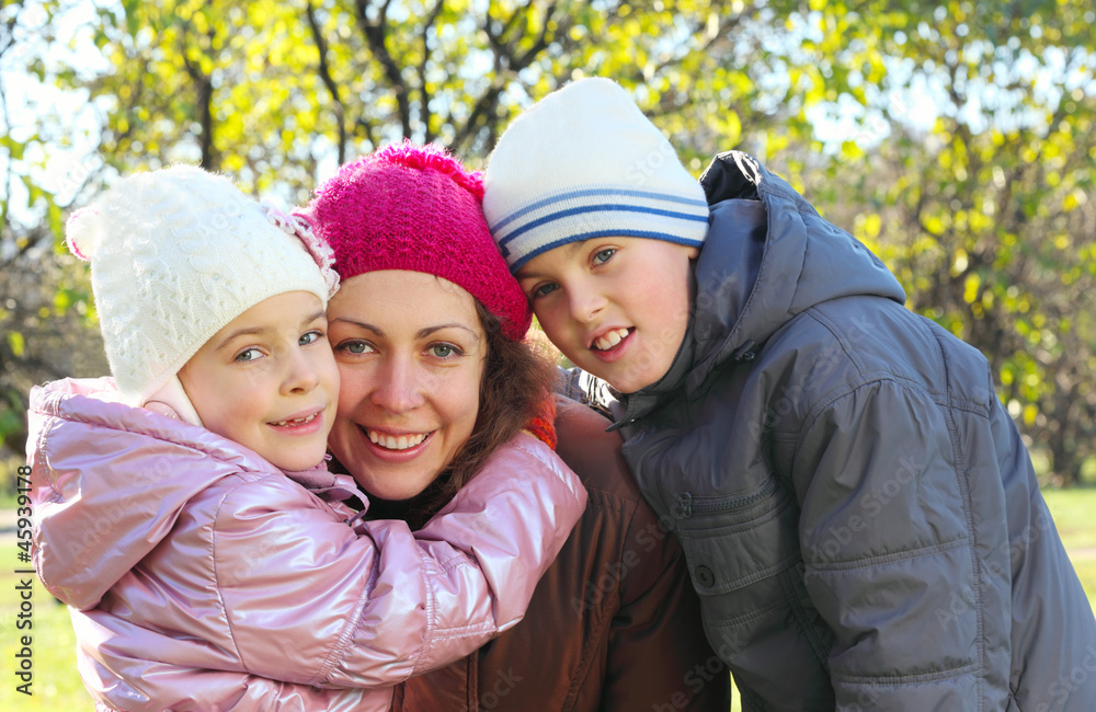 Smiling daughter, son hug mother in autumn forest Smiling daughter, son hug mother in autumn forest