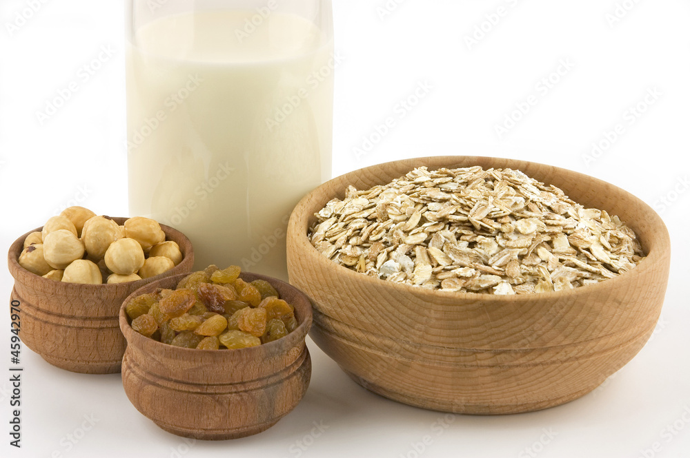 Healthy breakfast: oat flakes, raisins, hazelnuts, milk on white Healthy breakfast: oat flakes, raisins, hazelnuts, milk on white