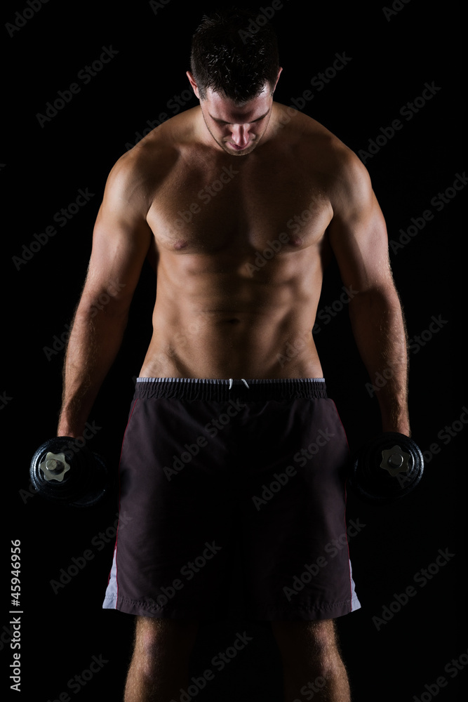 Strong male athlete holding dumbbell on black Strong male athlete holding dumbbell on black