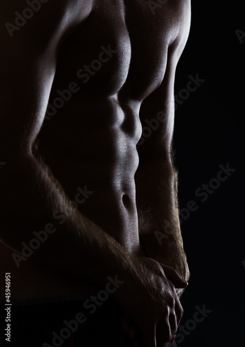 Closeup on sports man showing muscular body on black