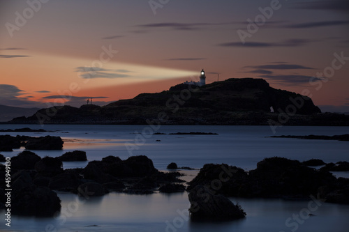 Lighthouse at sunset with light beam