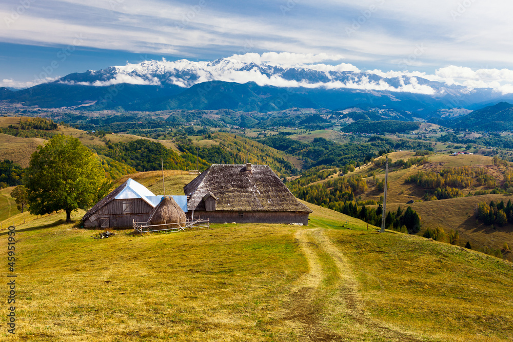 Landscape with a wooden traditional house and mountains in the b