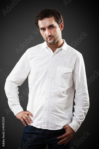 Young man standing with hand on hip isolated on gray background