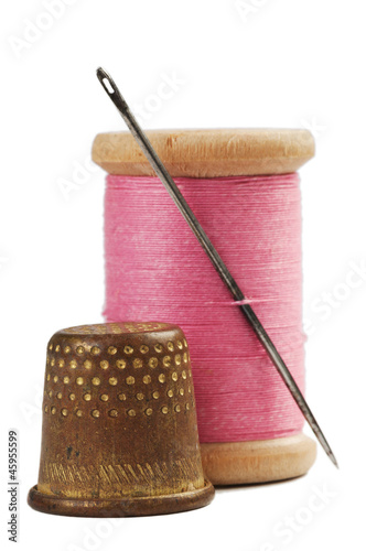 Old thimble and needle with pink thread