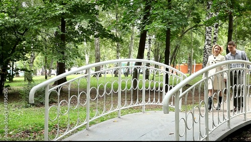 Двое влюблённых идут по мостику парка