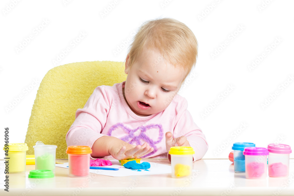 Little kid sitting at table playing with colorful clay Little kid sitting at table playing with colorful clay