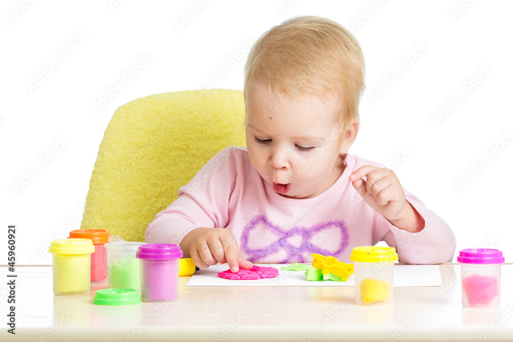 Little kid sitting at table playing with colorful clay Little kid sitting at table playing with colorful clay