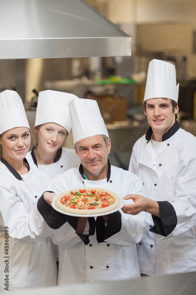 Four Chef's holding a pizza