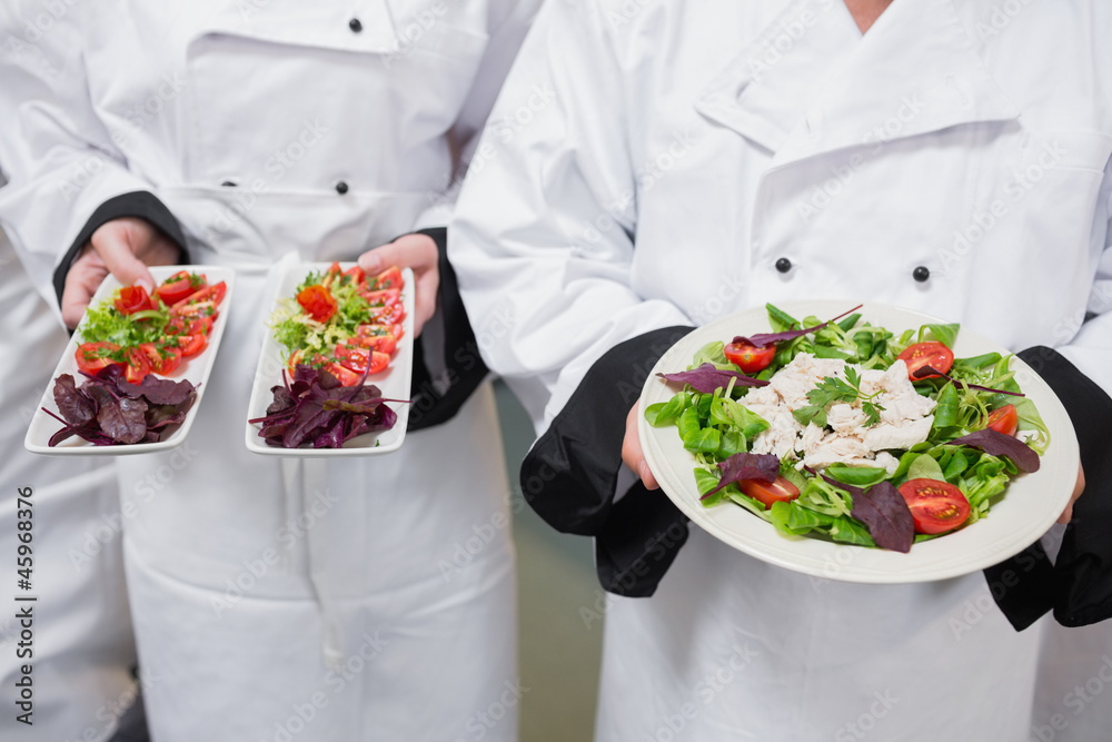 Chef's holding out their salads Chef's holding out their salads