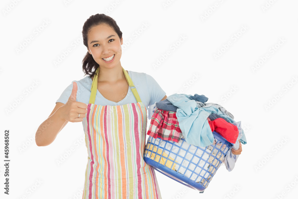 Woman carrying laundry basket and giving thumbs up Woman carrying laundry basket and giving thumbs up