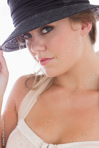 Woman in white holding black hat
