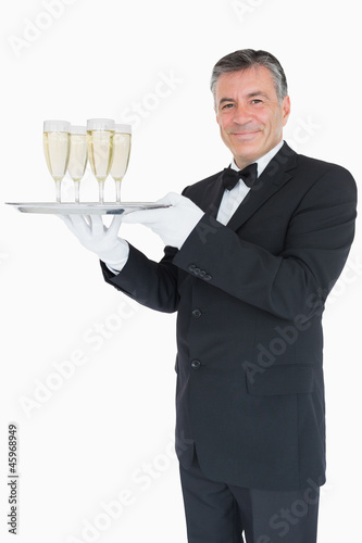 Smiling waiter holding tray with glasses with champagne