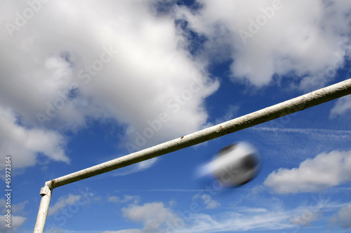 Blurred football and goalpost against a cloudy sky