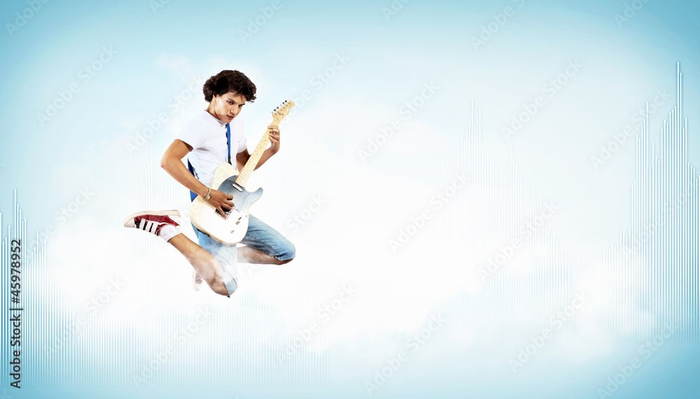 young man playing on electro guitar and jumping young man playing on electro guitar and jumping