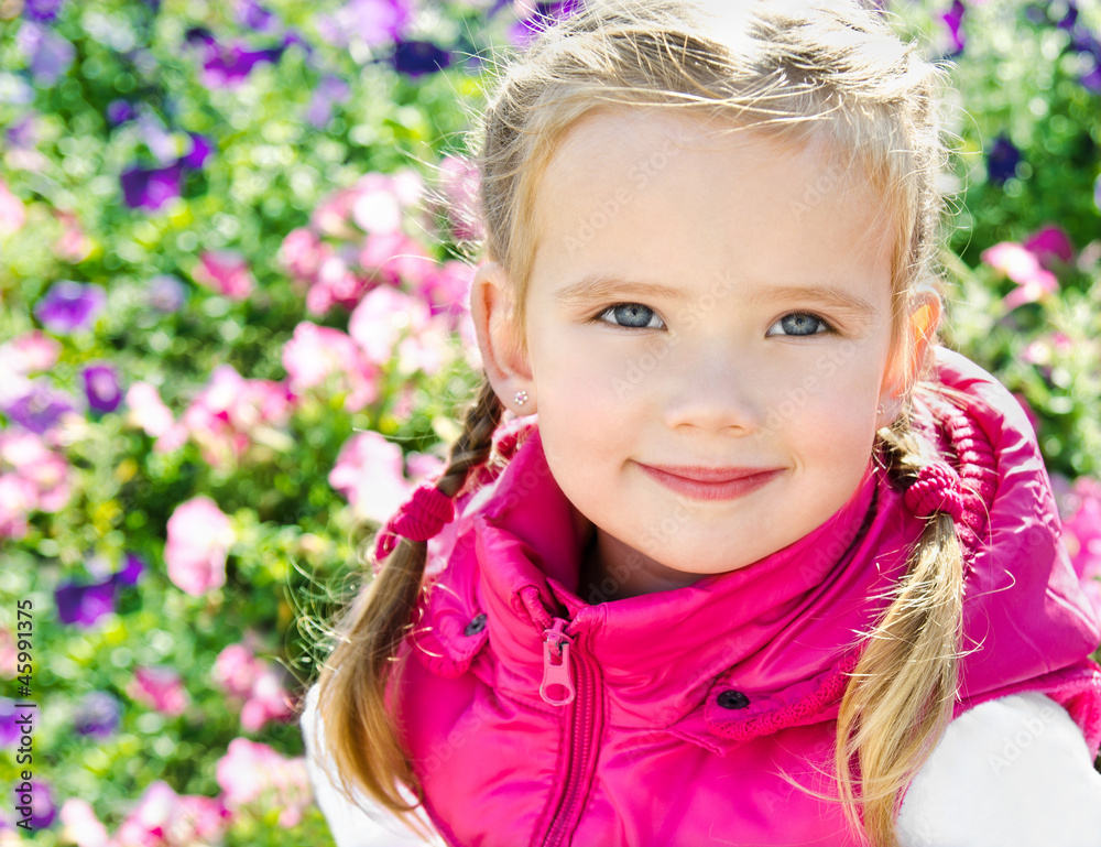 Outdoor portrait of cute little girl near the flowers