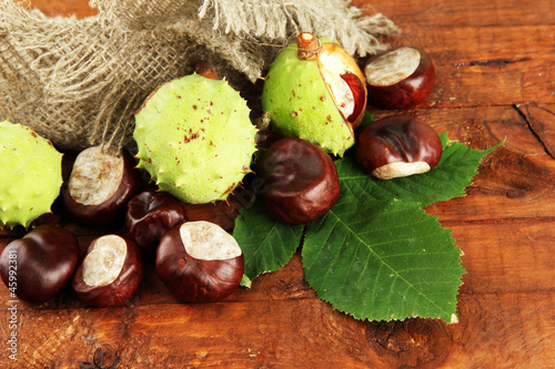 Chestnuts with leaves on wooden background