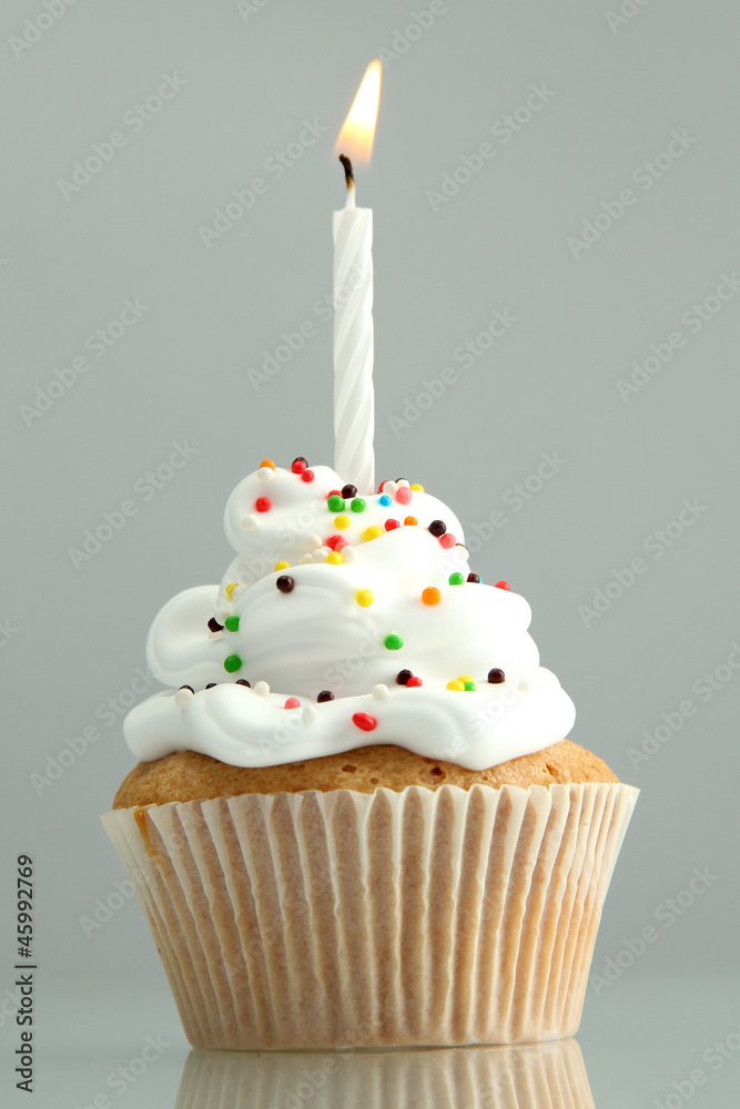 tasty birthday cupcake with candle, on grey background tasty birthday cupcake with candle, on grey background