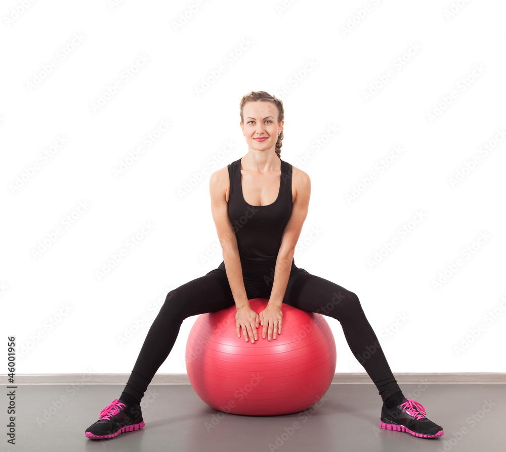 Athletic young woman on red ball in the gym