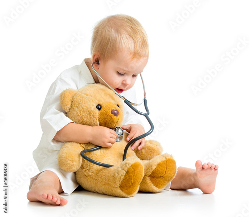 Adorable child with clothes of doctor and teddy bear over white photo