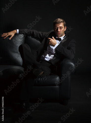 Handsome man in a tuxedo on couch