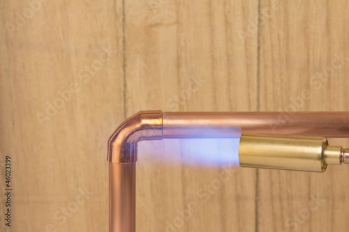 Plumbers hot gas soldering burner heating a copper pipe photo