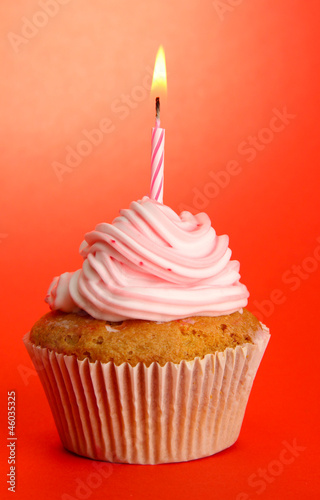 tasty birthday cupcake with candle  on red background