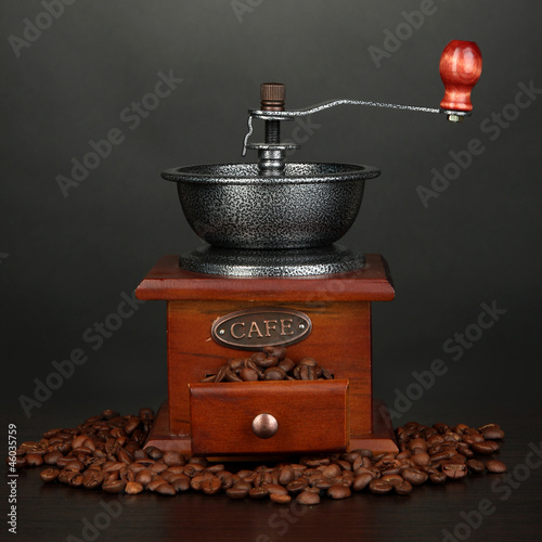 Coffee grinder with coffee beans on grey background