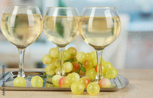 White wine in glass on salver on room background