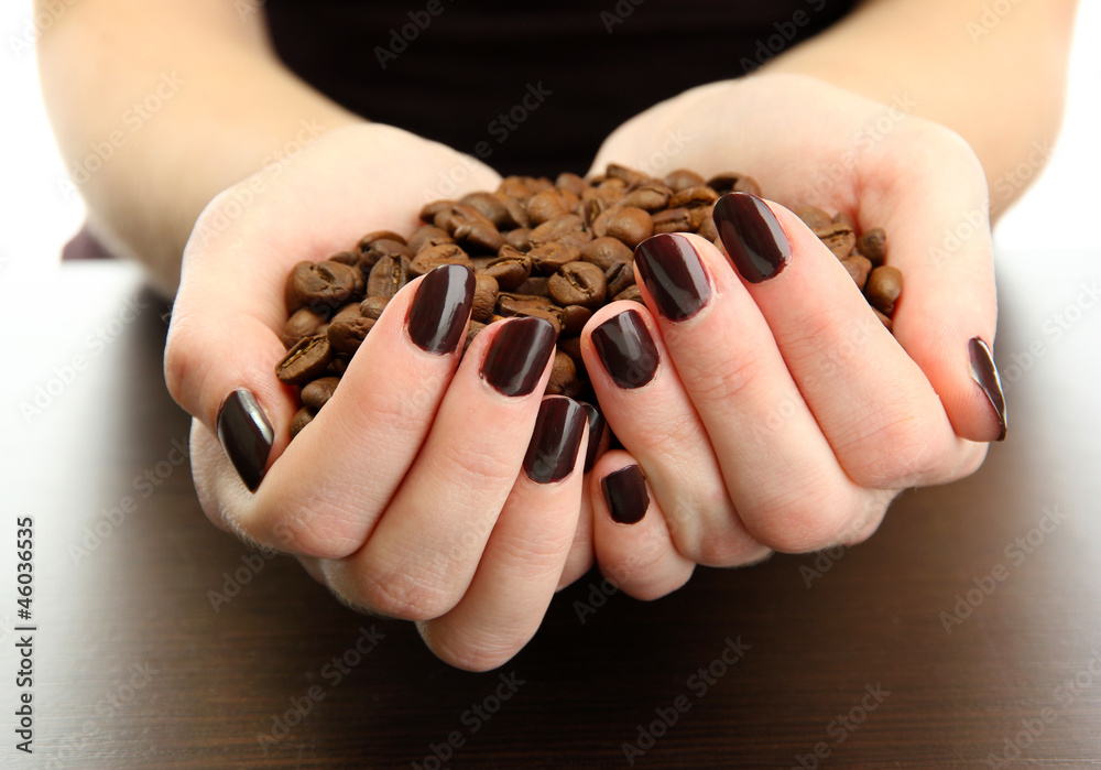 female hands with coffee beans, on wooden background female hands with coffee beans, on wooden background