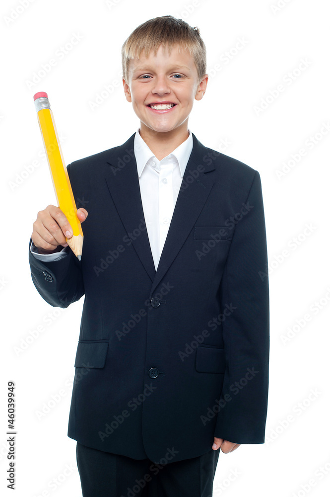 Cheerful young boy holding giant sized yellow pencil Cheerful young boy holding giant sized yellow pencil