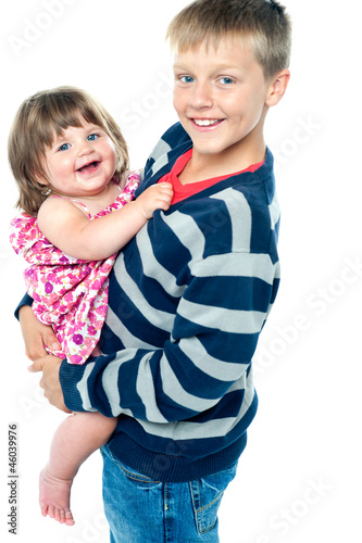 Loving young brother carrying his sweet little toddler sister