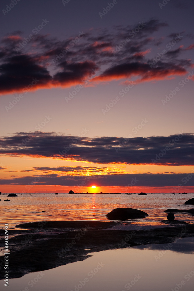 Naklejka premium Beautiful sunset at sea, large rocks in foreground