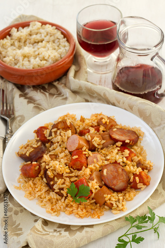 rice with chorizo and sausages on the plate and glass of wine
