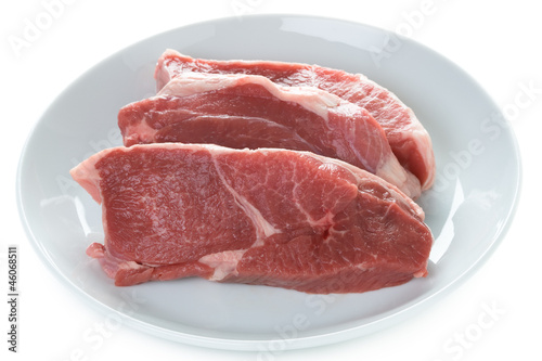 raw lamb leg steaks on a white plate isolated